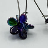 Flower-shaped pendant with metallic finish on a white background